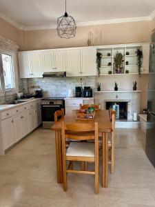 a kitchen with white cabinets and a wooden table at Mina's serene garden house in Kontokali
