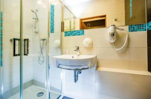 a bathroom with a sink and a shower at Hotel Wyspiański in Krakow