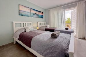 two beds in a bedroom with a view of the ocean at El Veril del Duque Apartment in Adeje +45 photos