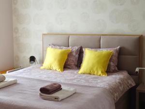 a bed with yellow pillows and two towels on it at Gracia apartman in Vrnjci