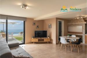 Una sala de estar con un sofá, un televisor y una mesa. en OurMadeira - OceanScape, tranquil, en Madalena do Mar
