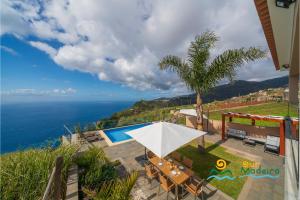 un patio con una mesa y una sombrilla blanca en OurMadeira - OceanScape, tranquil, en Madalena do Mar