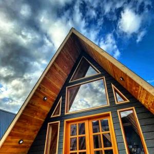 a house with a gambrel roof with windows at Cabaña Alpina 2 in Coñaripe
