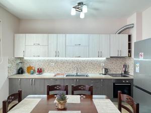 a kitchen with white cabinets and a table with chairs at Shkodra Apartments in Shkodër
