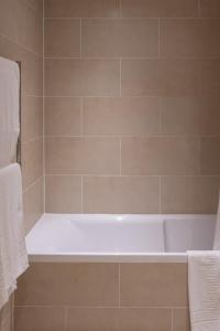 a white bath tub in a tiled bathroom at Broom House at Egton Bridge in Egton