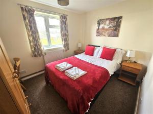 a bedroom with a bed with two towels on it at Cosy detached lodge, dog & child friendly with shared pools in Gunnislake +13 photos