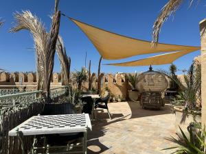 a patio with a table and chairs and a umbrella at Suite Les Trois Arches Djamila in Kairouan