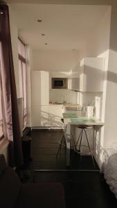 a white kitchen with a table and a counter at Studio Hypercentre proche gares et métro in Lille +4 photos