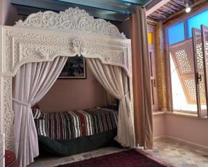 uma cama de dossel num quarto com uma janela em Suite Dôme Jasmin em Bin Rhilouf