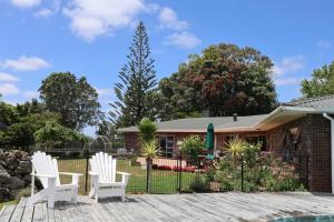 a house with two white chairs and a fence at Luxury Countryside Retreat - Totara Valley in Ohaeawai