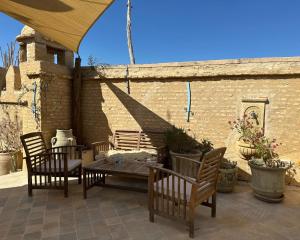 a patio with a table and chairs and a brick wall at Suite Dôme Jasmin in Bin Rhilouf +10 photos