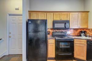 Una cocina con refrigerador negro y gabinetes de madera. en Entire 2BD, Near Forsyth Park, en Savannah 7 fotos más