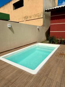 a swimming pool on a deck with a building at Casa lazer Atafona in São João da Barra