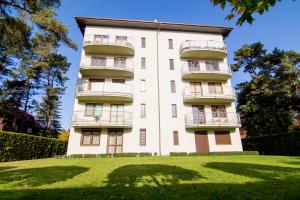 a tall white building with balconies on a lawn at Apartamenty Świnoujście - Rezydencja Żeromskiego in Świnoujście