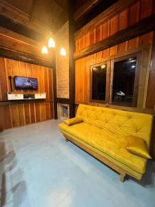 a yellow couch in a room with a tv at Cabana Maktub in Nova Veneza
