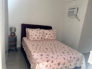 a bedroom with a bed with a pink comforter at Apê Praia do Forte in Cabo Frio
