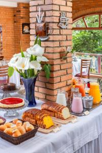 a table with bread and cakes and a vase of flowers at Estalagem Spiller in Monte Verde
