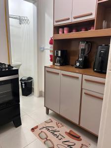 a kitchen with white cabinets and a kitchen rug at Apê Praia do Forte in Cabo Frio