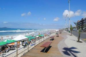 a beach with people sitting on the sand and the ocean at Apê Praia do Forte in Cabo Frio