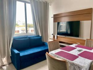 a living room with a blue couch and a table and a window at Apê Praia do Forte in Cabo Frio
