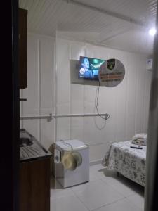 Habitación pequeña con cama y TV en la pared. en Nosso Bosque Hospedaria, en Penha