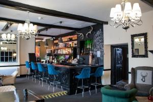 a bar with blue bar stools in a room at The Scole Hotel in Scole