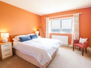 a bedroom with orange walls and a bed and a window at Bryn Mor in Benllech