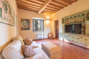 Una sala de estar con un sofá y un televisor de pantalla plana. en Windrose La Casa degli Angeli, en Montaperti