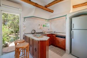 a kitchen with wooden cabinets and a white refrigerator at Cala di Volpe - Esclusiva Villa con Piscina Privata in Abbiadori