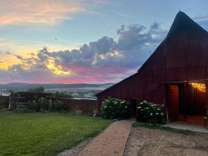 a red barn with a sunset in the background at Daisy Glamping Tent at Zenzen Gardens in Paonia +6 photos