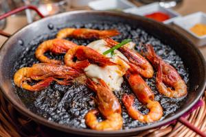 a pan filled with shrimp and eggs on a table at Parrot’s House in Lloret de Mar