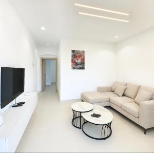 a white living room with a couch and a tv at Appartement Palms Abidjan in Abidjan
