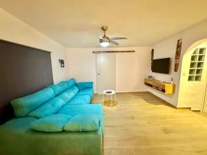 a living room with a blue couch and a tv at Villa Narok in Tarajalejo