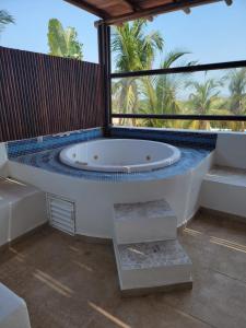 une grande baignoire dans une pièce avec des palmiers dans l'établissement Terrasol Diamante, à Acapulco
