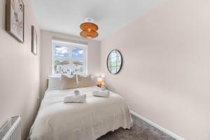 ein weißes Schlafzimmer mit einem großen Bett und einem Fenster in der Unterkunft 15 Mins to Sizewell C - Driveway Parking - Contractor Friendly - 2 Bedroom in Saxmundham