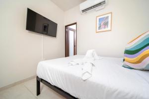 um quarto com uma cama branca e uma TV de tela plana em Room 3 Vibrant Walkable Hub in Santurce em San Juan