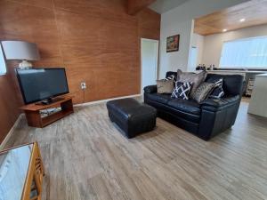 a living room with a black leather couch and a flat screen tv at Hope Villa in Muri