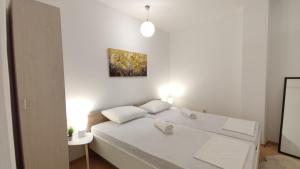 a white bedroom with a white bed with two pillows at Apartmani Tarik in Mostar