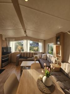 a living room with a couch and a table at Chalet De VeerWater in Recreatiepark De Veerstal in Lathum