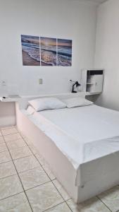 ein weißes Bett in einem Zimmer mit einem Bild an der Wand in der Unterkunft Pousada Martanha in Porto Belo
