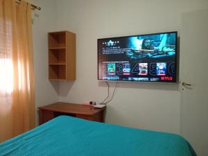 ネウケンにあるAlquiler Familiar, Depto 2 dormitorios, SE PAGA AL LLEGAR, ANTES NO, en planta bajaの壁に薄型テレビが取り付けられた寝室
