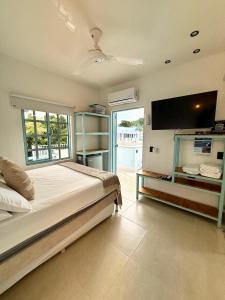 a bedroom with a large bed and a flat screen tv at Cabaña Villa Jardín - Aldea Doradal - Santorini Colombiano in Doradal