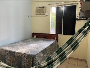 a hammock in a room with a bed and a window at Ap COP 30 in Ananindeua
