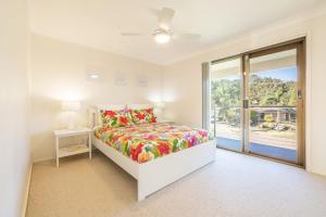 a white bedroom with a bed and a window at The Verandah fantastic child friendly home in Anna Bay