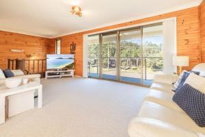 a living room with a white couch and a large window at The Verandah fantastic child friendly home in Anna Bay