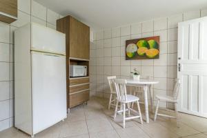 a kitchen with a table and a white refrigerator at CUSTO X BENEFÍCIO COM CONFORTO -AR COND-wifi in Florianópolis +4 photos