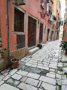 a stone alley with a building with doors and plants at Apartments and rooms by the sea Rovinj - 24536 in Rovinj