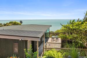 a house with a deck and a view of the ocean at G SPOT UPPER LEVEL with spa in Raglan