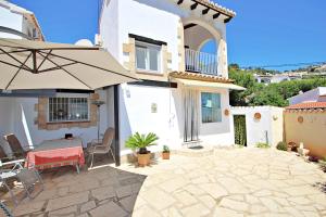 un patio con una mesa y una sombrilla en Beate - holiday bungalow with pool in Moraira, en Moraira