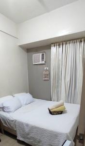 a bedroom with a white bed with a window at 2-BR COZY condo 200mbpsFiberWiFi/Netflix/pool/WFH in Manila